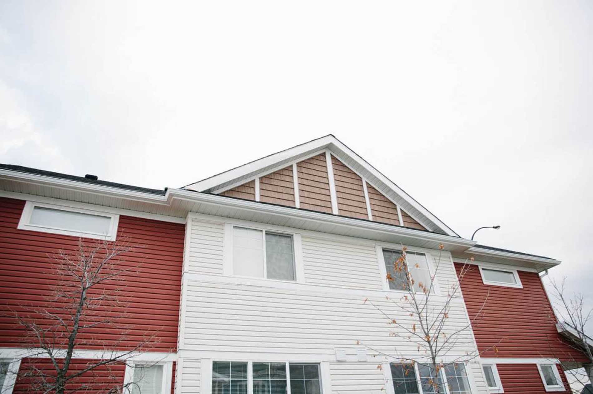 Multi-story house with red and white siding and gabled roof.