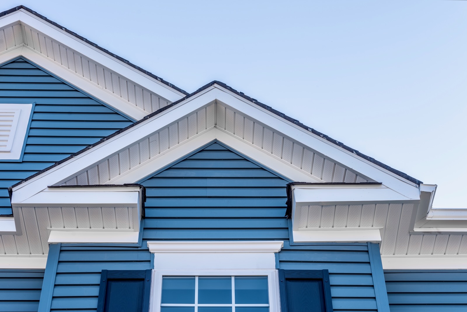 Close-up of blue house gables with white soffit, siding, and trim